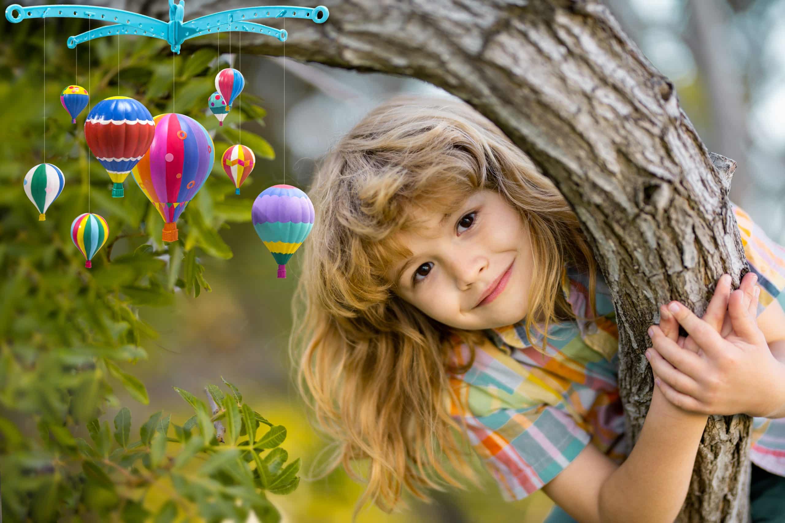 Cute little kid boy enjoying climbing on tree on summer day. Kid happily lying in a tree hugging a big branch.